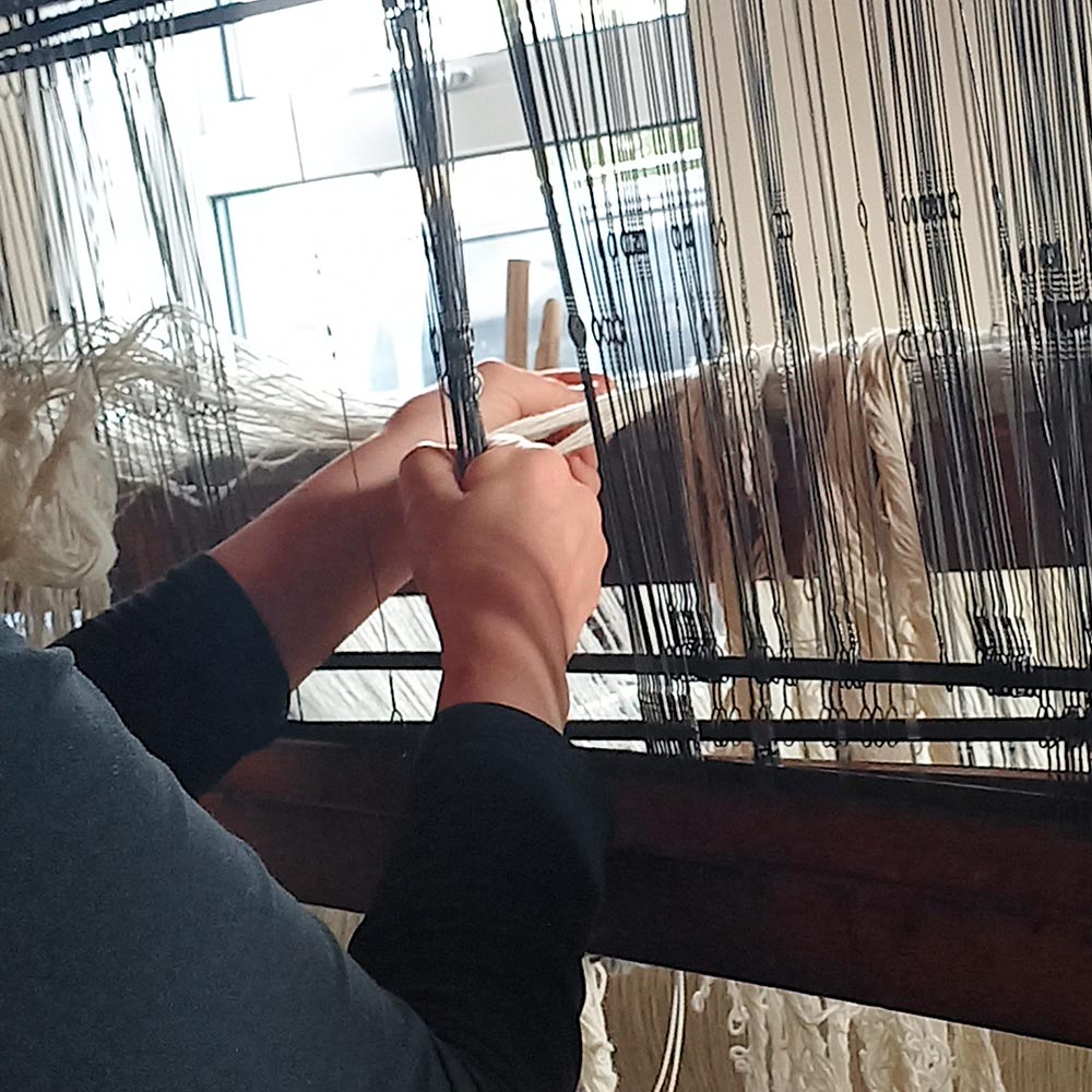 A colourful selection of woolen spools on the floor beside a loom.