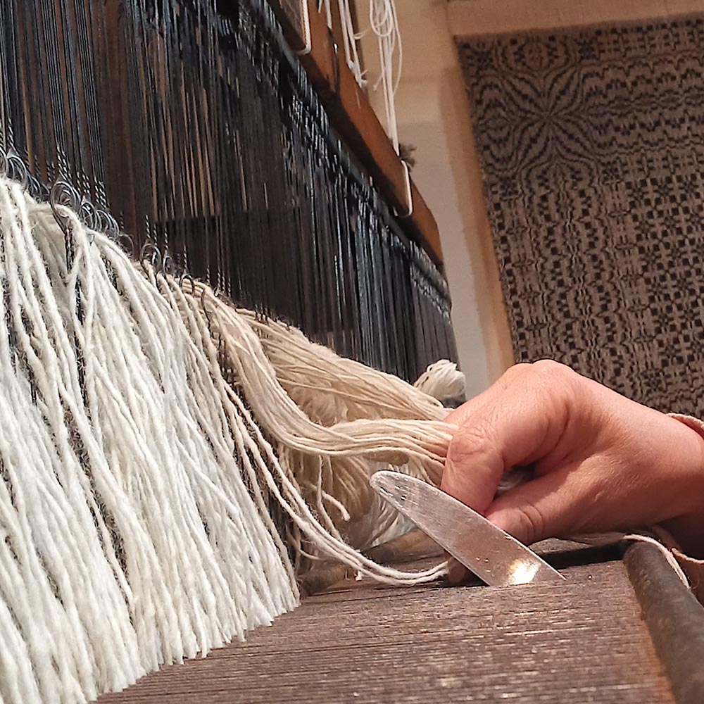 A colourful selection of woolen spools on the floor beside a loom.