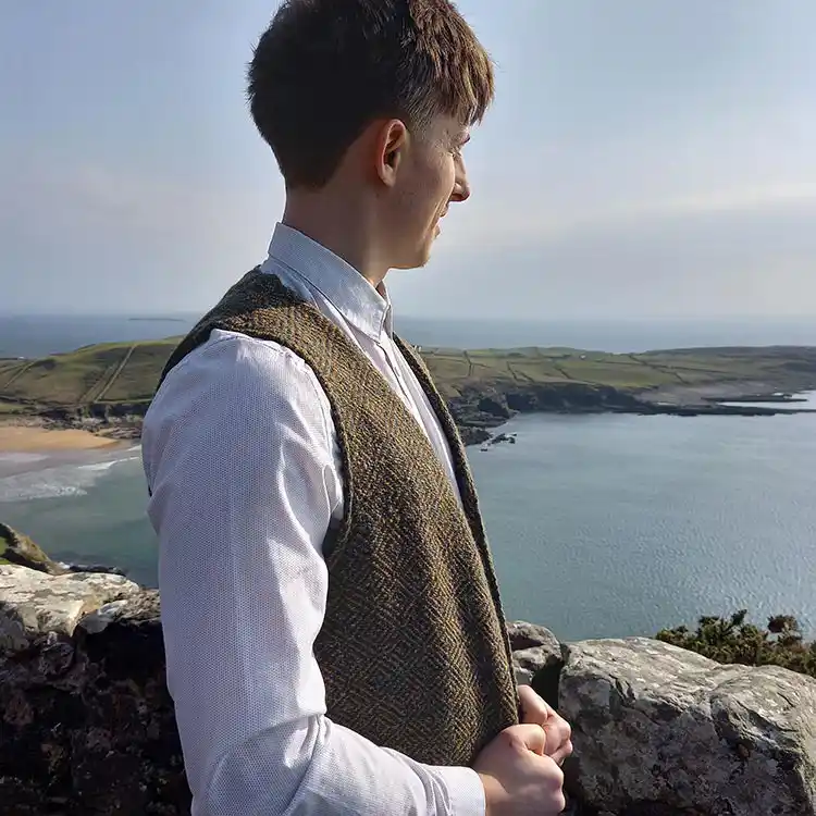 A young man wearing a tweed waistcoat looks out across Donegal Bay.